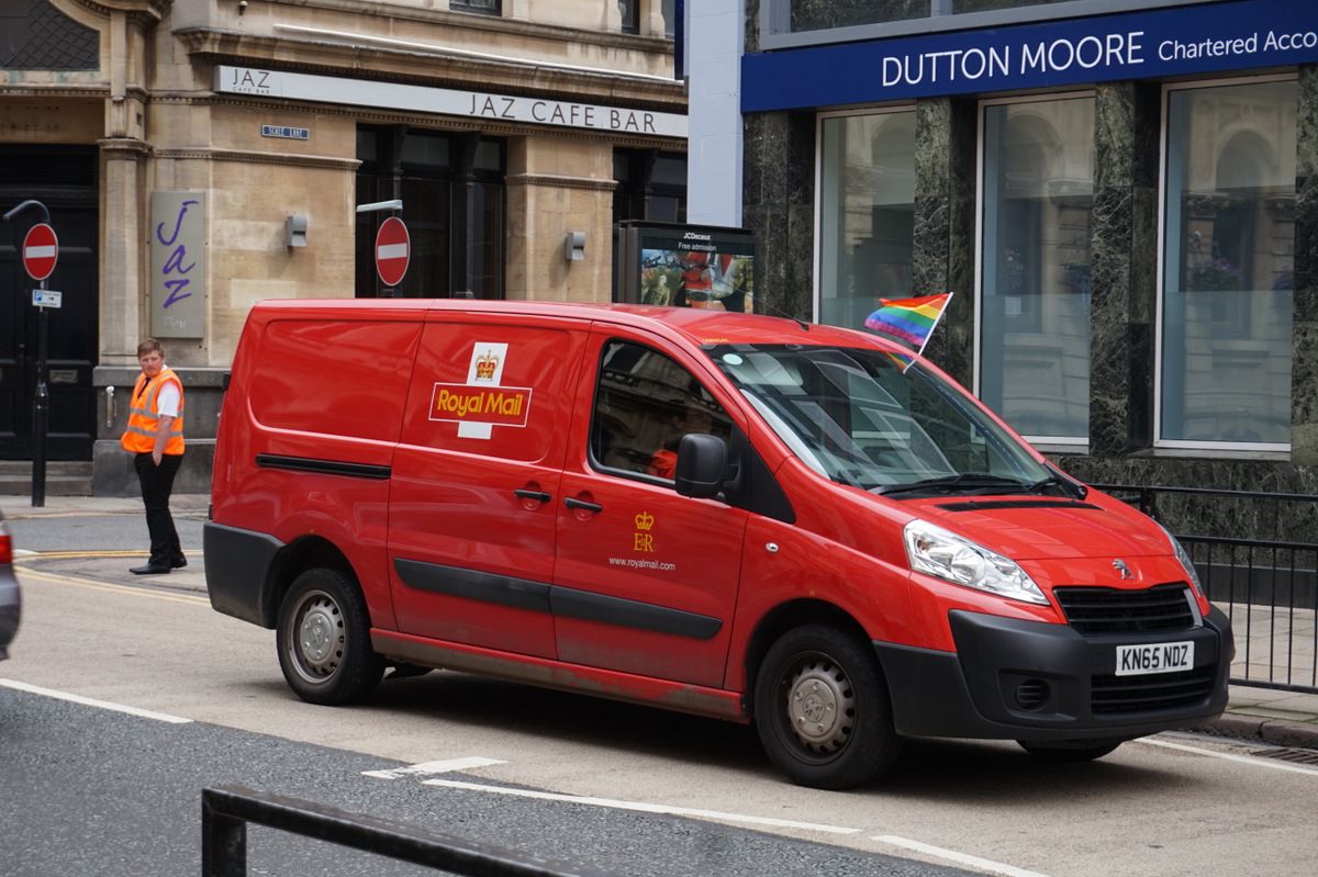 A red Royal Mail delivery van on a city street